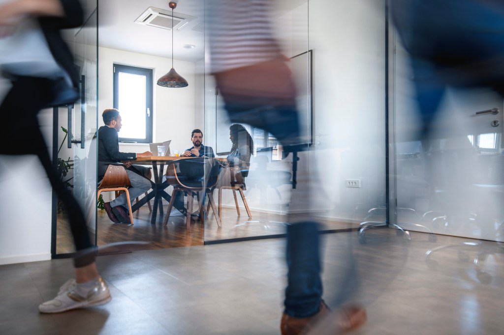 Businesspeople in Conference Room and Colleagues Walking By