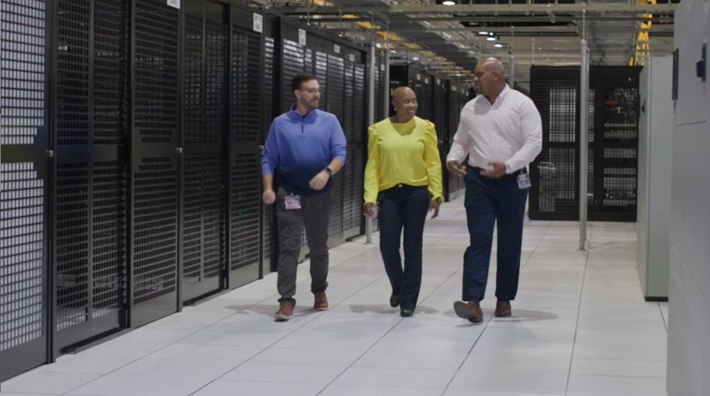 Three people walking through a data center